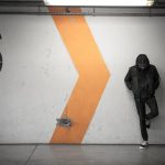 Man in hoodie standing by a wall