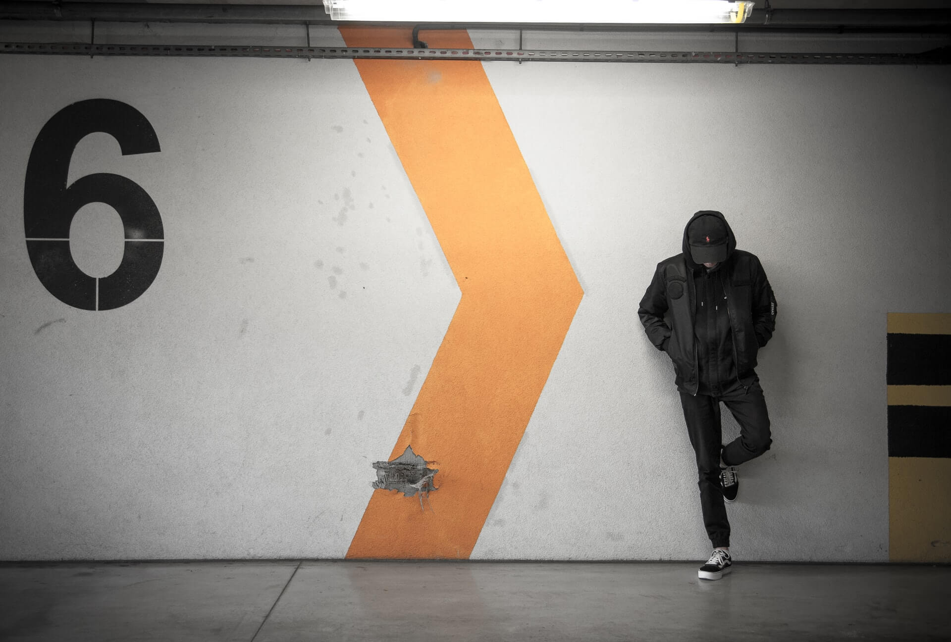 Man in hoodie standing by a wall